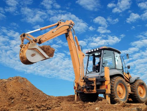 Excavator Loader with rised backhoe standing in sandpit with over cloudscape sky