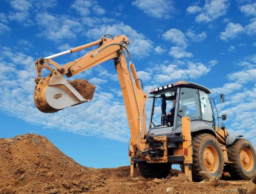 Excavator Loader with rised backhoe standing in sandpit with over cloudscape sky