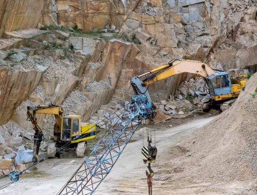 Mining in the granite quarry. Working mining machine - old crane and digger. Mining industry.