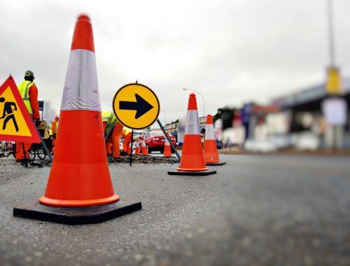 Traffic cone used in road re-construction, men at work